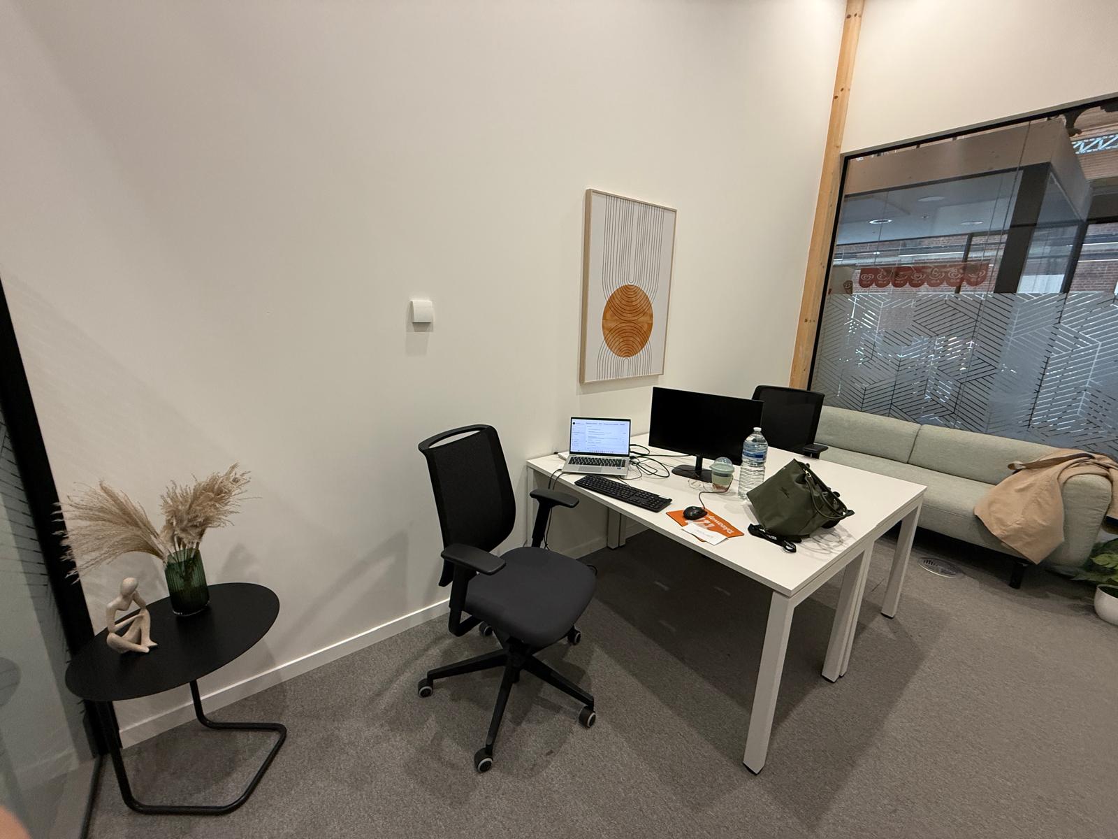 Bureau de travail de Kimmy Nossa : plan de travail épuré, ordinateur portable et double écran.